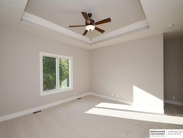 unfurnished room with carpet floors, a tray ceiling, and ceiling fan