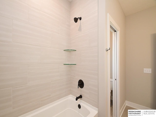 bathroom featuring toilet and tiled shower / bath