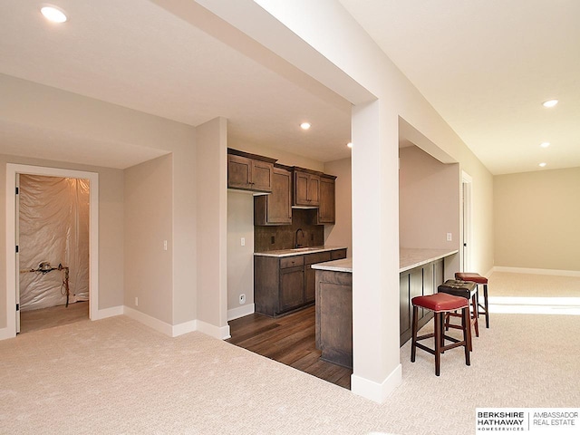 kitchen with tasteful backsplash, sink, a breakfast bar area, and dark colored carpet