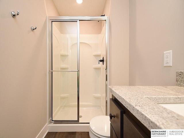 bathroom featuring hardwood / wood-style flooring, vanity, toilet, and a shower with shower door