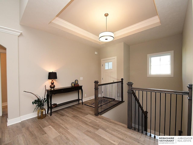 staircase with wood-type flooring, ornamental molding, and a tray ceiling