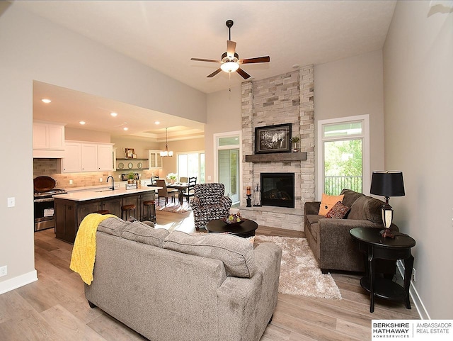 living room with a fireplace, light hardwood / wood-style flooring, ceiling fan, and a healthy amount of sunlight