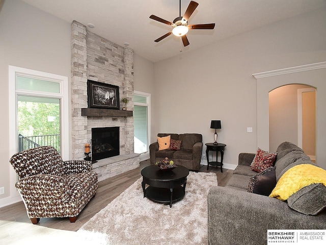 living room featuring a stone fireplace, ceiling fan, and hardwood / wood-style floors