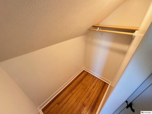 walk in closet with hardwood / wood-style flooring and vaulted ceiling