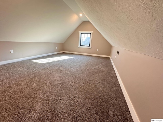 bonus room featuring carpet flooring, vaulted ceiling, and a textured ceiling