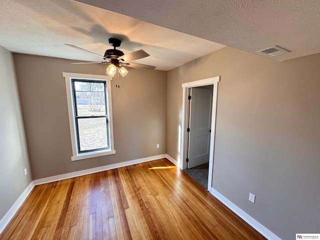 unfurnished room with hardwood / wood-style floors, ceiling fan, and a textured ceiling