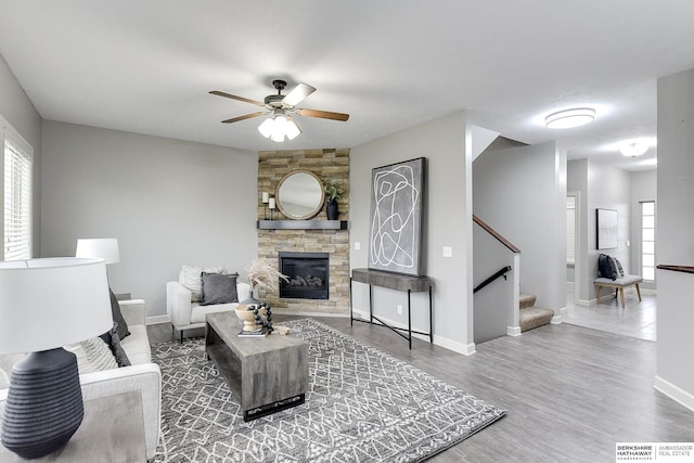 living room with hardwood / wood-style floors, a stone fireplace, and ceiling fan