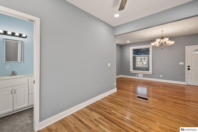 interior space featuring ceiling fan with notable chandelier, light hardwood / wood-style floors, and sink