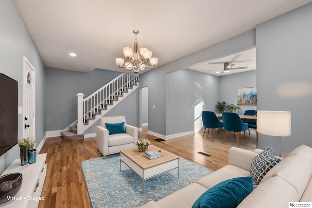 living room with ceiling fan with notable chandelier and wood-type flooring