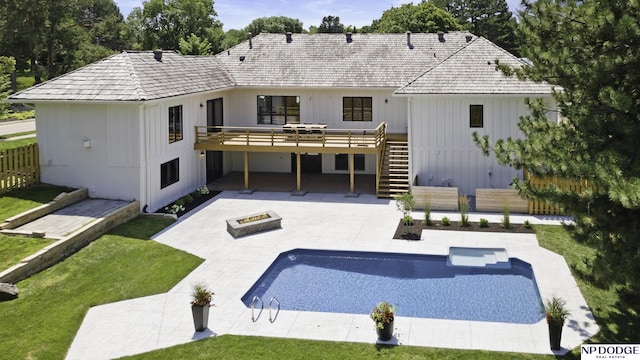 back of house featuring a lawn, a pool side deck, a patio, and a fire pit