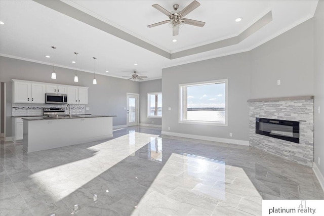 living room with a fireplace, crown molding, and a tray ceiling