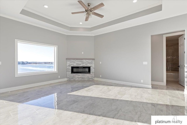 unfurnished living room featuring a raised ceiling, ceiling fan, a fireplace, and ornamental molding