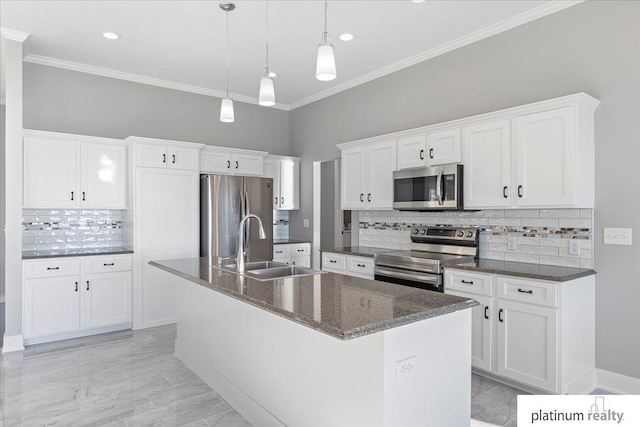 kitchen with a center island with sink, white cabinets, tasteful backsplash, decorative light fixtures, and stainless steel appliances