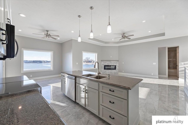 kitchen featuring a center island with sink, stainless steel dishwasher, a tray ceiling, and sink