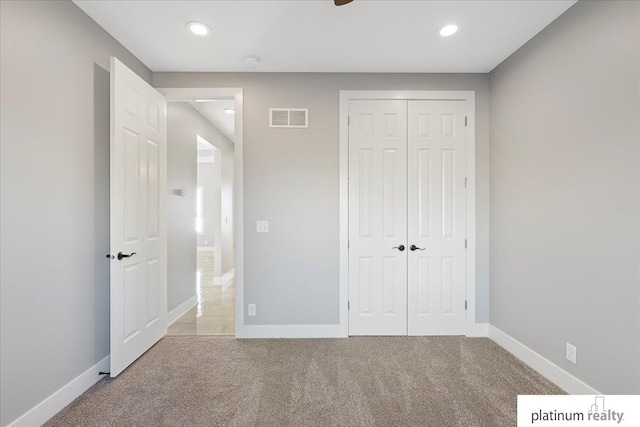 unfurnished bedroom with light colored carpet, a closet, and ceiling fan