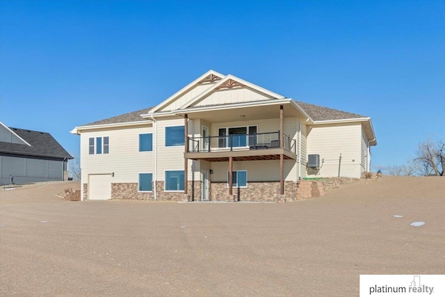 back of property with central AC, a balcony, and a garage