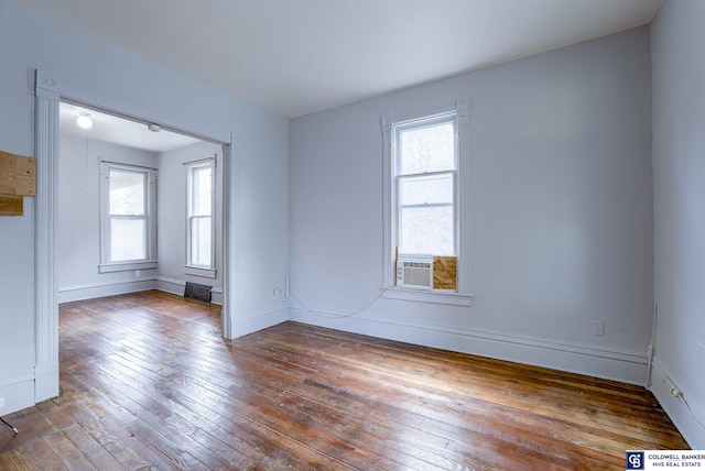 unfurnished room featuring hardwood / wood-style floors, cooling unit, and a wealth of natural light