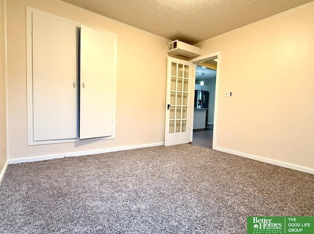 carpeted spare room with a textured ceiling and french doors