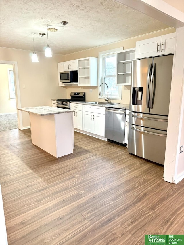 kitchen featuring white cabinets, pendant lighting, a kitchen island, and stainless steel appliances