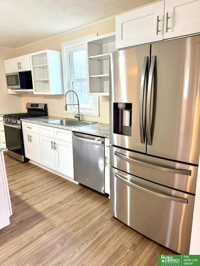 kitchen with light stone counters, sink, white cabinetry, and stainless steel appliances