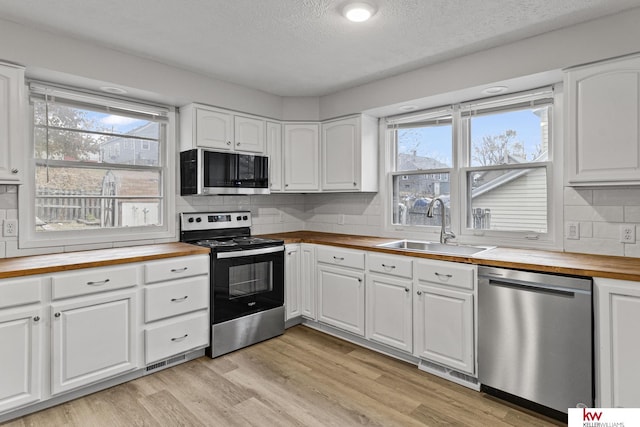 kitchen featuring white cabinetry, stainless steel appliances, and wood counters