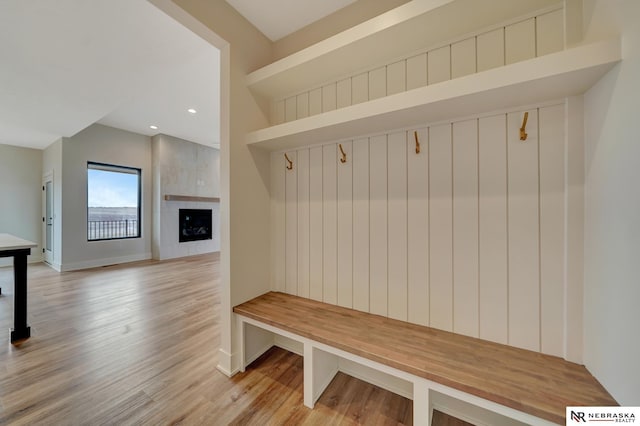 mudroom with a tile fireplace and light hardwood / wood-style flooring