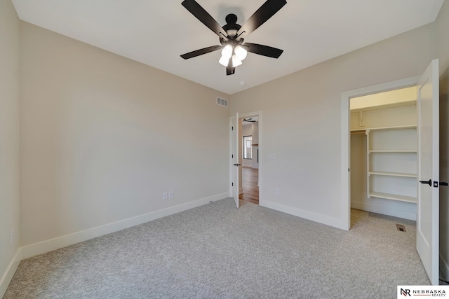 unfurnished bedroom with light carpet, a closet, a spacious closet, and ceiling fan