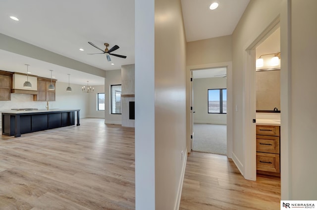 kitchen with a fireplace, ceiling fan with notable chandelier, wood-type flooring, and decorative light fixtures