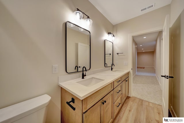 bathroom with hardwood / wood-style floors, vanity, and toilet