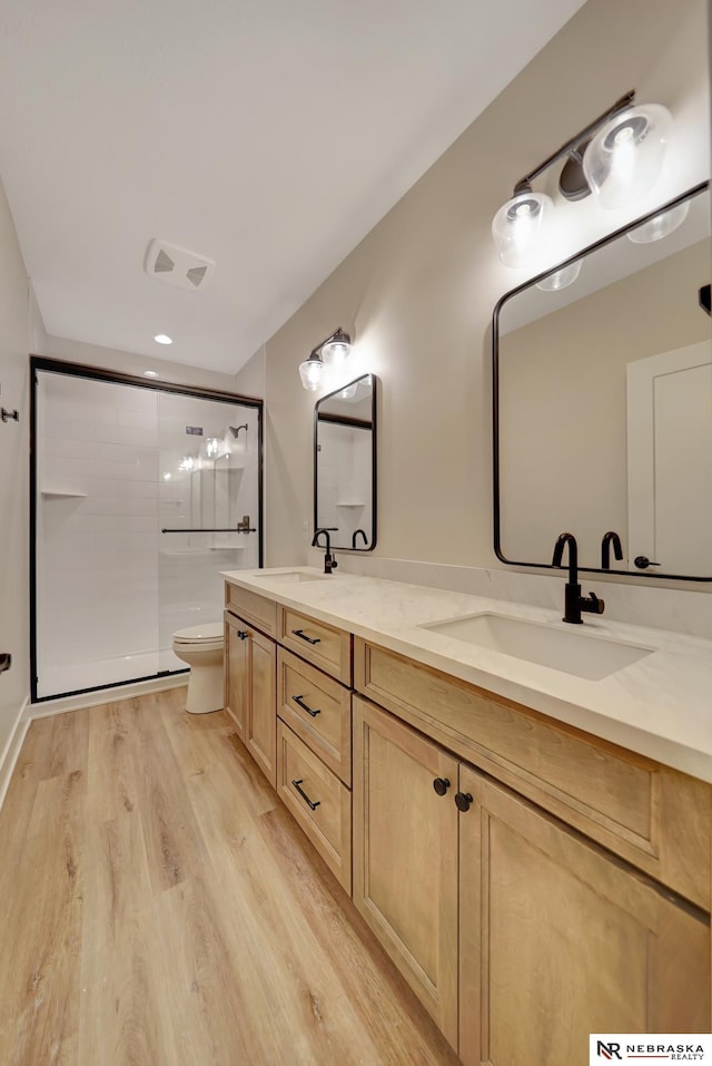 bathroom featuring toilet, vanity, wood-type flooring, and walk in shower