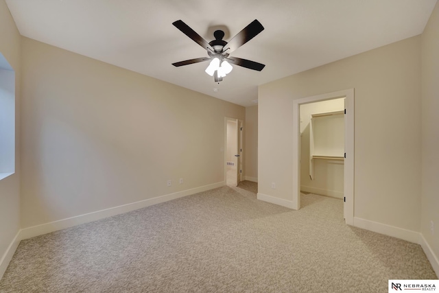 unfurnished bedroom with ceiling fan, light colored carpet, a walk in closet, and a closet