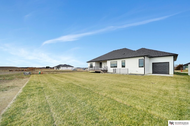 back of property featuring a garage, a deck, and a yard