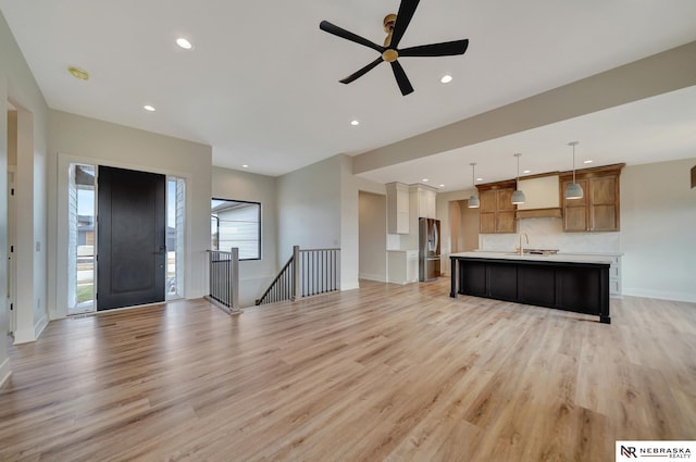 unfurnished living room with ceiling fan, light hardwood / wood-style floors, and sink