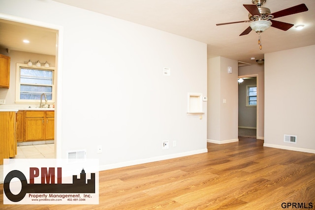 empty room with ceiling fan, sink, and light hardwood / wood-style floors