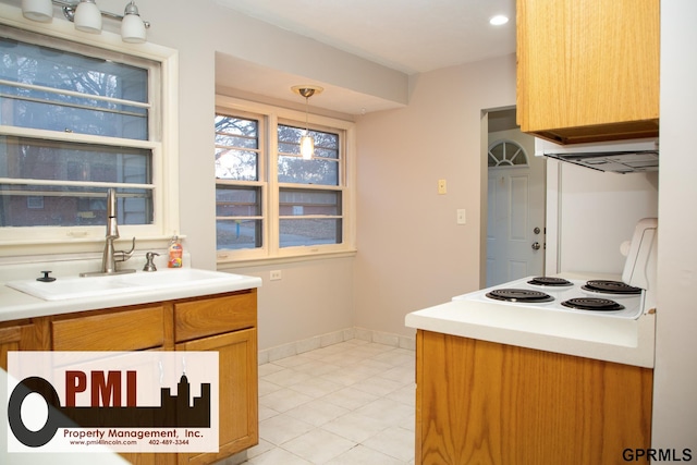 kitchen featuring hanging light fixtures, cooktop, and sink