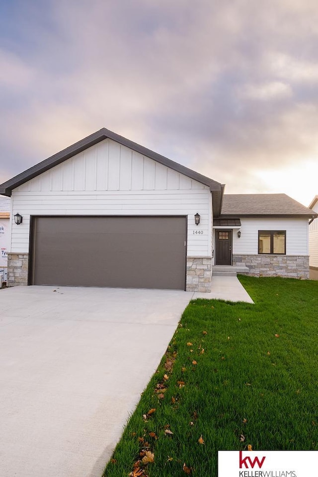 1450 Montana St, Superior, NE 68978 - view of front facade with stone siding, driveway, a front yard, a garage, and board and batten siding