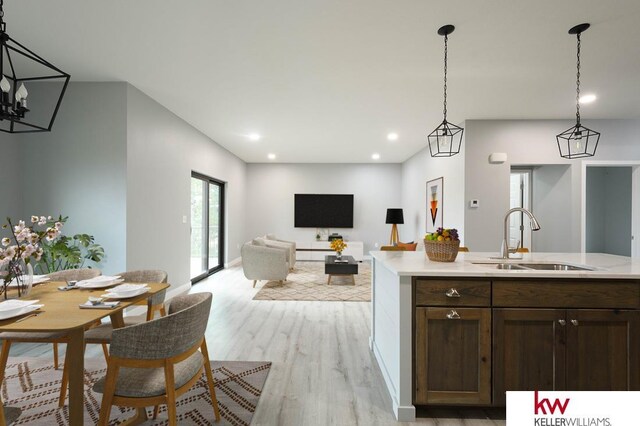 1450 Montana St, Superior, NE 68978 - kitchen featuring a sink, light wood-type flooring, light countertops, decorative light fixtures, and dark brown cabinets