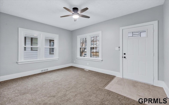 carpeted entrance foyer with a textured ceiling and ceiling fan