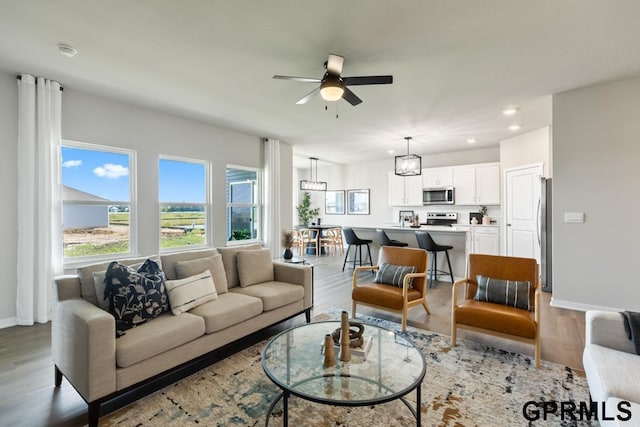 living room with light hardwood / wood-style floors and ceiling fan with notable chandelier