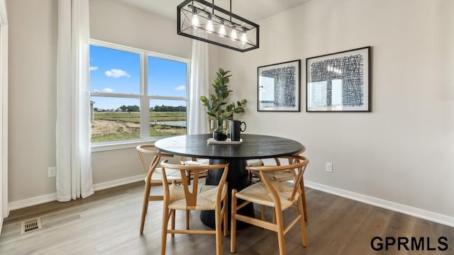 dining space with hardwood / wood-style floors and a notable chandelier