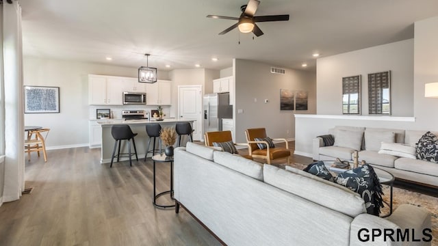 living room featuring dark hardwood / wood-style flooring and ceiling fan with notable chandelier