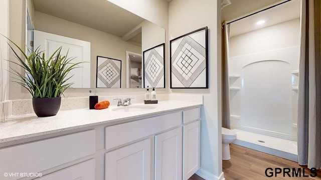 bathroom with walk in shower, toilet, vanity, and hardwood / wood-style flooring