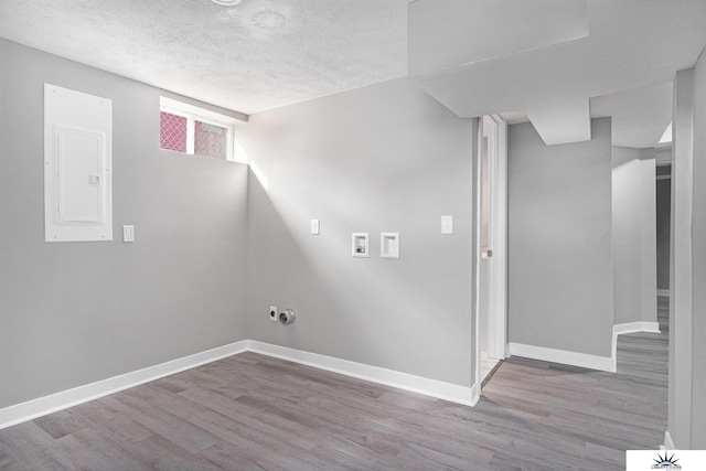 washroom with light wood-type flooring, hookup for a washing machine, a textured ceiling, and electric panel