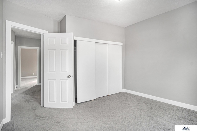 unfurnished bedroom with light carpet, a textured ceiling, and a closet