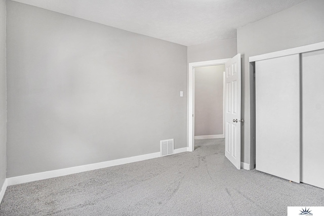 unfurnished bedroom with light carpet and a closet