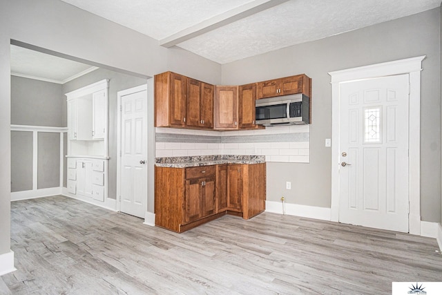 kitchen with decorative backsplash, a textured ceiling, and light wood-type flooring