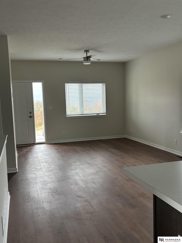 spare room with ceiling fan, a healthy amount of sunlight, and dark wood-type flooring