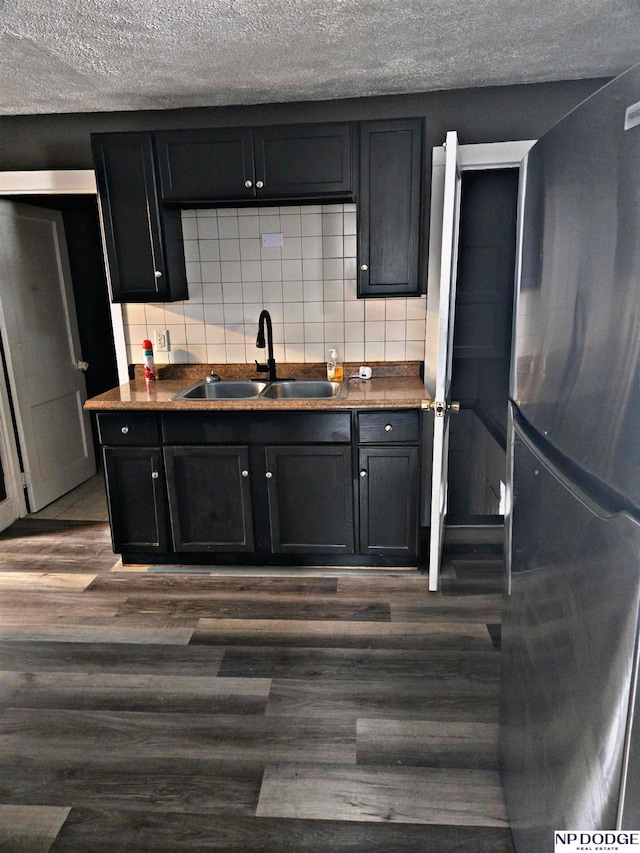 kitchen with tasteful backsplash, stainless steel refrigerator, sink, and dark hardwood / wood-style floors