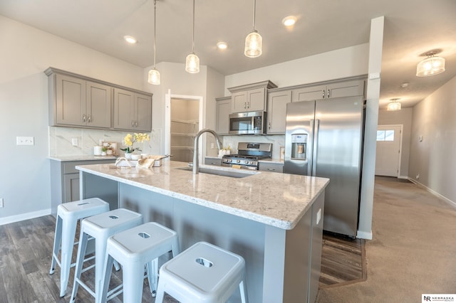 kitchen featuring stainless steel appliances, sink, a breakfast bar area, decorative backsplash, and pendant lighting