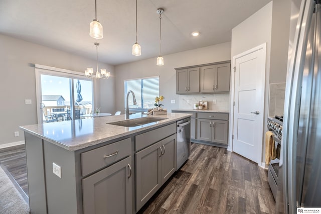 kitchen with hanging light fixtures, an island with sink, stainless steel appliances, gray cabinets, and sink